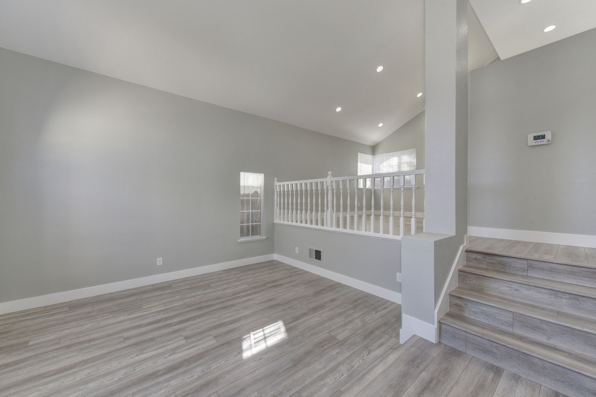 Spacious modern interior with minimalist design, wooden flooring, and bright lighting.